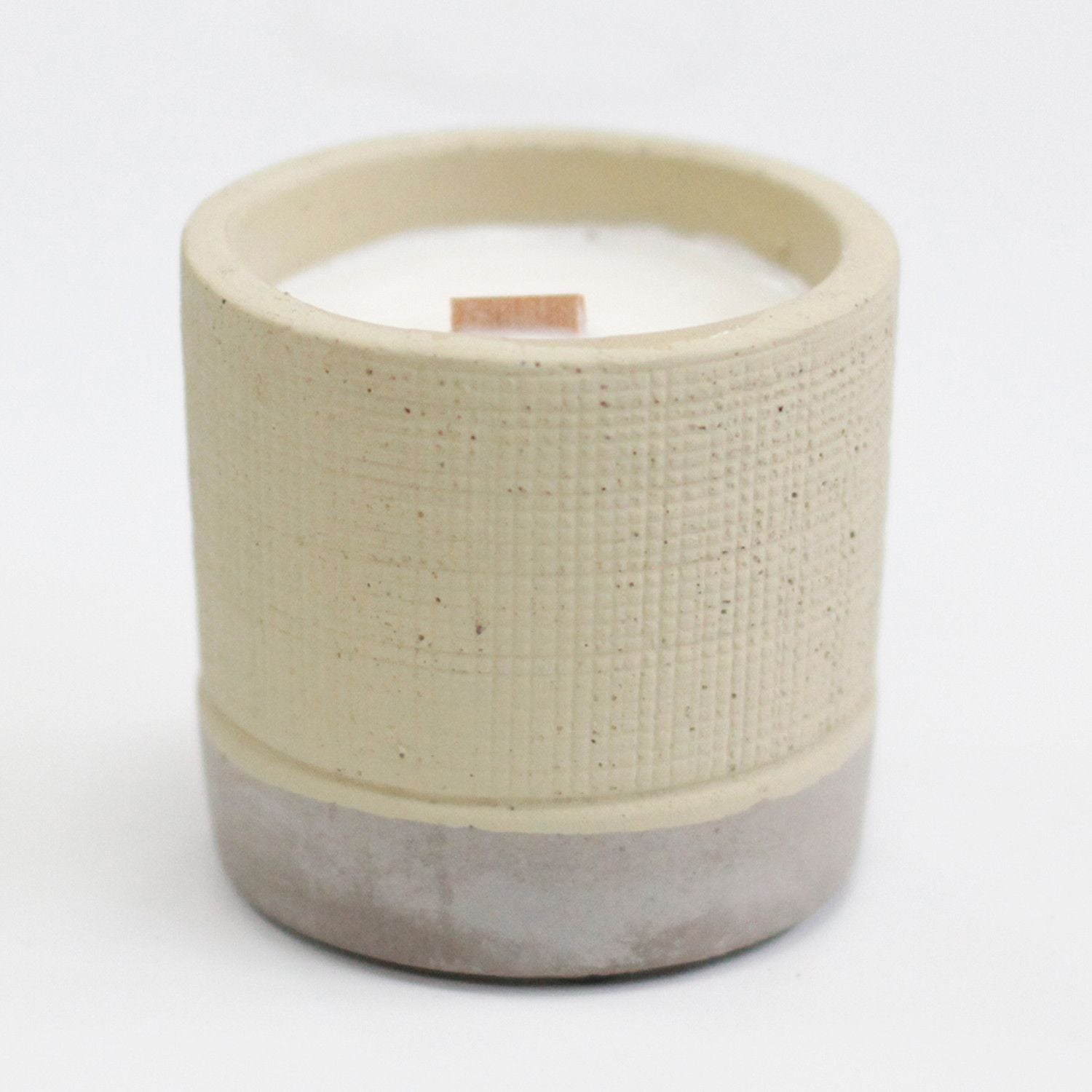 Ceramic candle holder with a textured beige top and concrete base on a white background